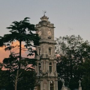 Stunning view of a historic clock tower at dusk with a yellow taxi passing by, Istanbul.